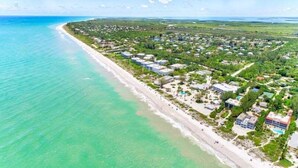 An aerial view of a coastal area with a beach, residential buildings, and greenery. - Sandy Bend 2 2 Bedroom Condo (Sanibel)