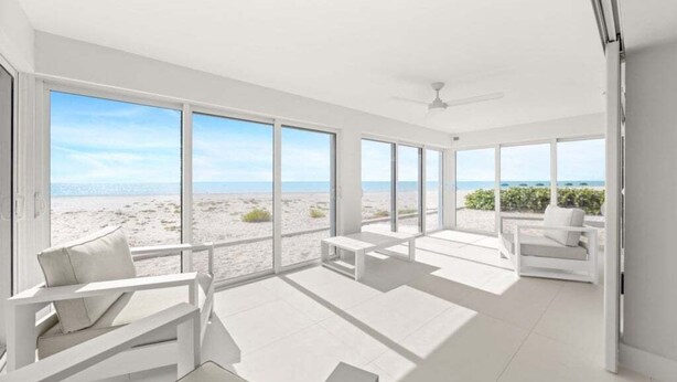 A spacious room with large windows offering a view of the beach. There are white sofas and a ceiling fan. - Sandy Bend 2 2 Bedroom Condo (Sanibel)