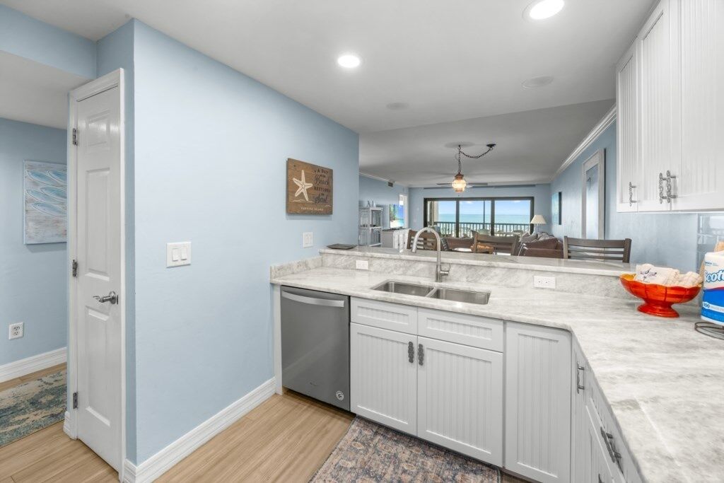 A modern kitchen with a large island, white cabinetry, and a view to the living area.