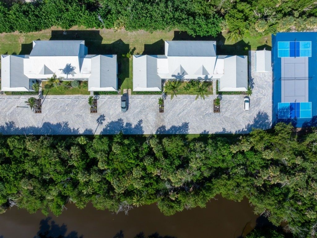 A long building with a flat roof, surrounded by dense greenery and a body of water.