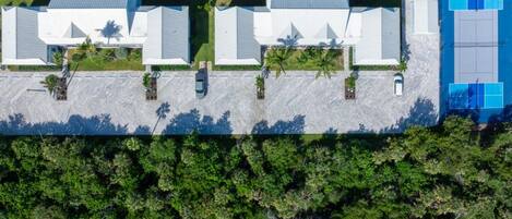 A long building with a flat roof, surrounded by dense greenery and a body of water.