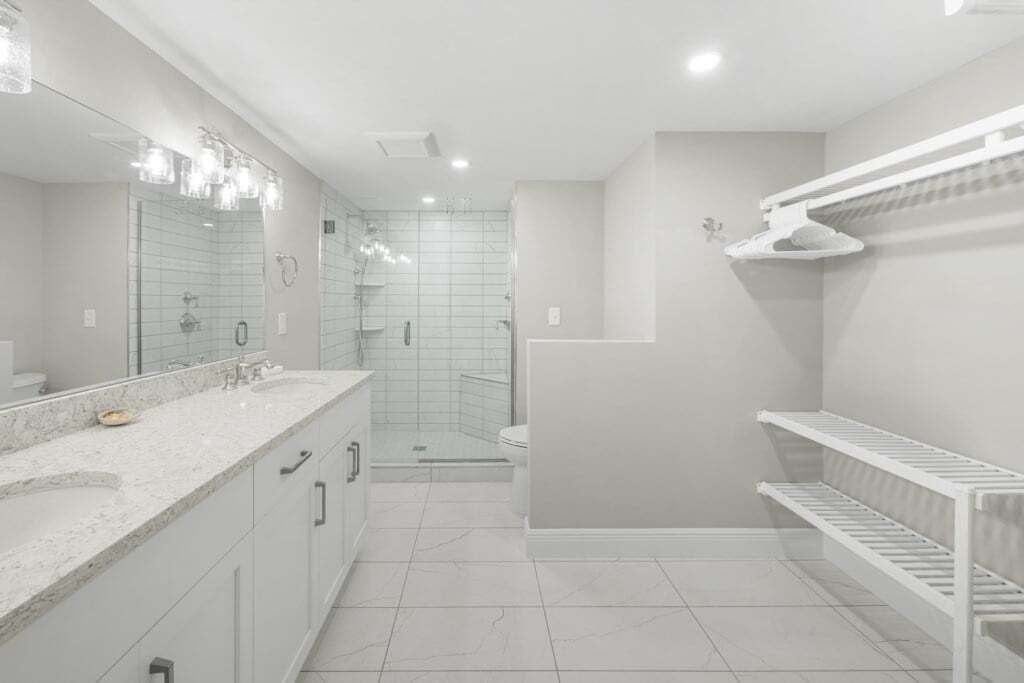 A modern bathroom with a large mirror, a shower, and a toilet.
