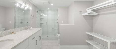 A modern bathroom with a large mirror, a shower, and a toilet.