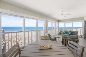 Een balkon met uitzicht op strand en zee, voorzien van een tafel, stoelen en een bank.