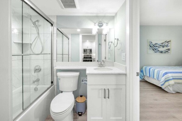 A modern bathroom with a glass shower enclosure, a white sink, and a toilet. - Sandy Bend 8 2 Bedroom Condo (Sanibel)