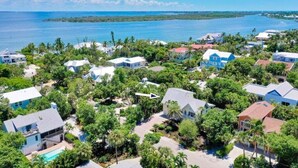 A coastal residential area with houses surrounded by lush greenery and a view of the ocean.