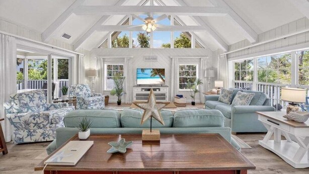 A spacious living room with a high ceiling, large windows, and a central star decoration.