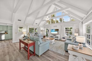 A spacious living area with a high ceiling, large windows, and a view of the outdoors. - Bird Of Paradise 4 Bedroom Home (Captiva)