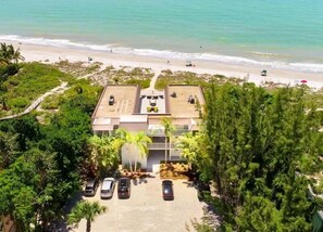 A beachfront property with a parking area, a building with a flat roof, and a view of the ocean. - Sandy Bend 3 2 Bedroom Condo (Sanibel)
