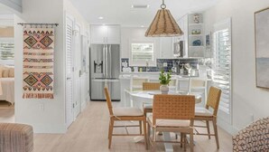 Una cocina moderna con armarios blancos, una isla central y una lámpara colgante.