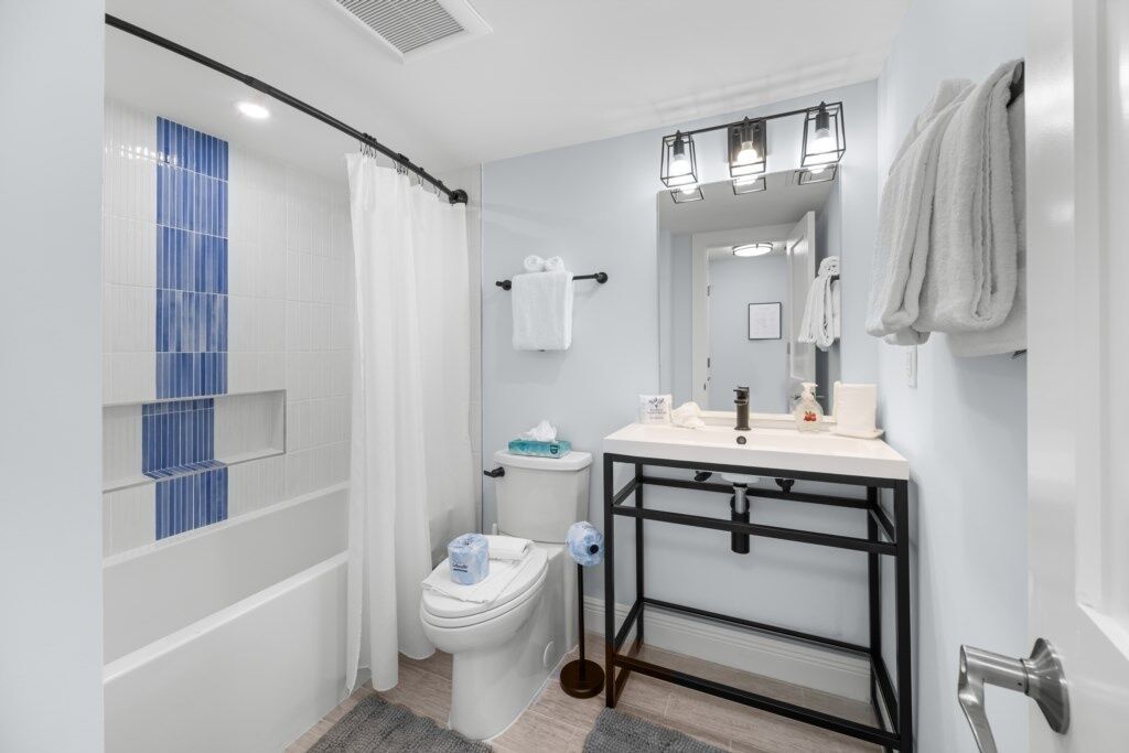 A modern bathroom with a white sink, black metal frame, and a shower curtain.