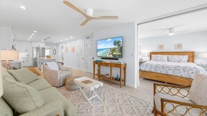 A modern hotel room with a bed, a TV, a desk, and a dining area. - Sandy Bend 1 2 Bedroom Condo (Sanibel)