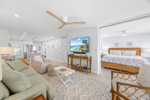 A modern hotel room with a bed, a TV, a desk, and a dining area. - Sandy Bend 1 2 Bedroom Condo (Sanibel)