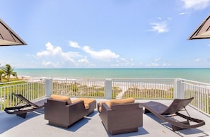 A balcony with wicker furniture and a view of the beach. - Sandy Bend 1 2 Bedroom Condo (Sanibel)