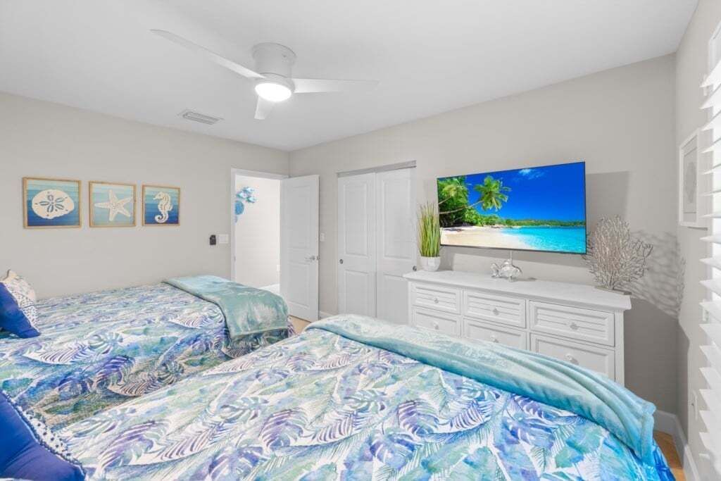 A bedroom with two beds, a TV, and a wardrobe.