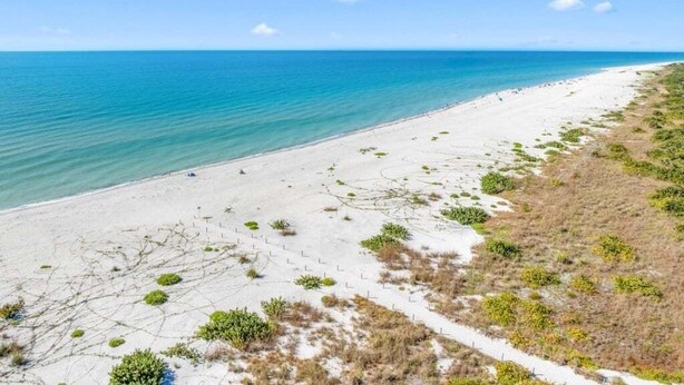 A beach with a clear view of the ocean and a sandy path leading to the water. - Blind Pass Unit G201 2 Bedroom Condo (Sanibel)