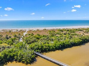 A coastal area with a bridge over a river, surrounded by greenery and a beach. - Blind Pass Unit G201 2 Bedroom Condo (Sanibel)