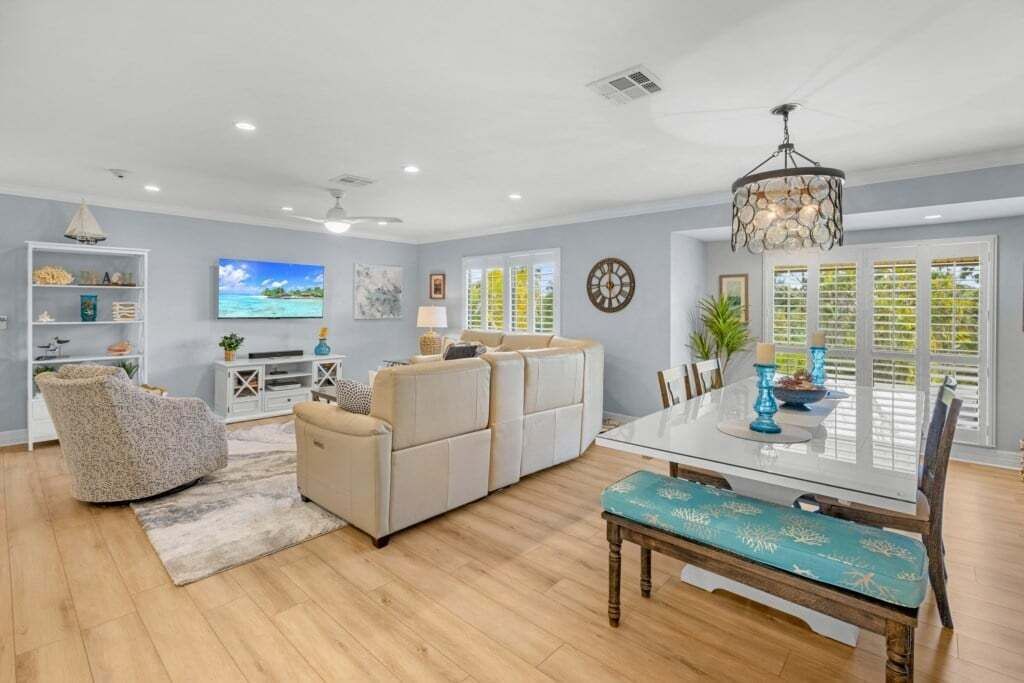 A spacious living room with a sofa, a dining table with chairs, a TV, and a chandelier.