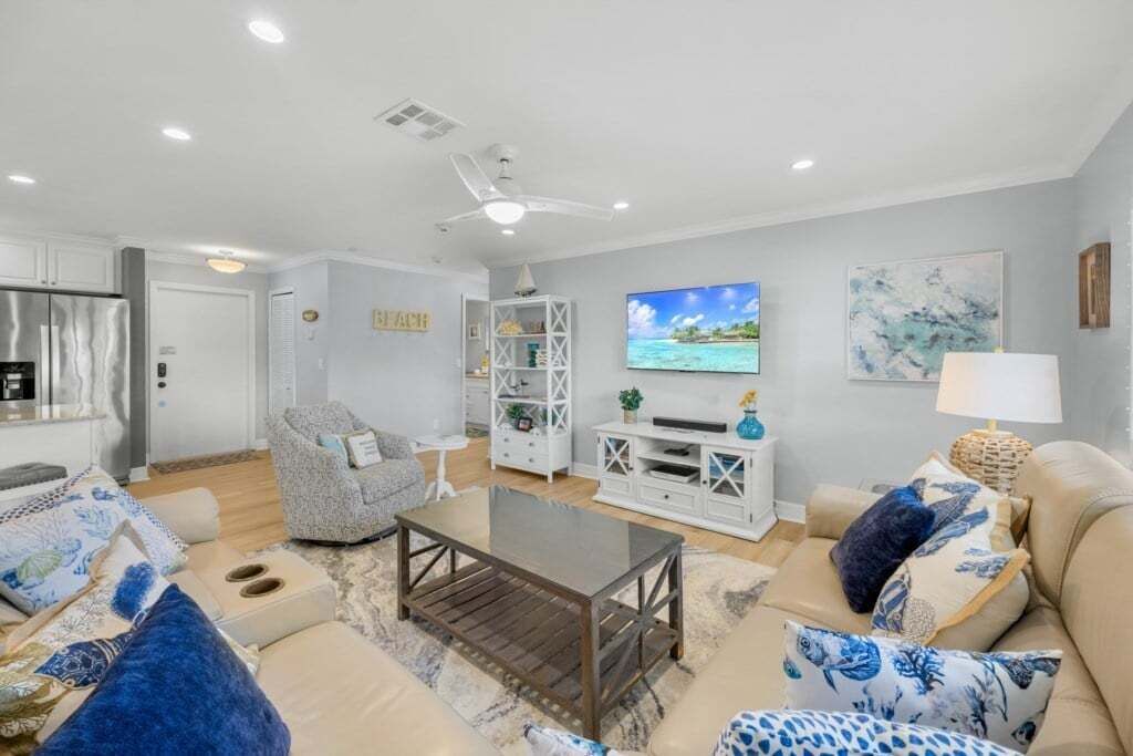 Una sala de estar con sofá, sillón, mesa de centro, televisor y mueble de entretenimiento.
