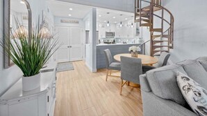 A modern kitchen with white cabinets, a central island, and pendant lighting. - Coquina 3f 3 Bedroom Condo (Sanibel)