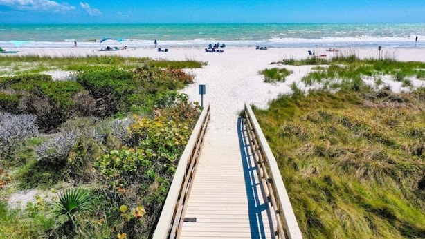 A wooden boardwalk leading to a beach with clear skies and calm waters. - Coquina 3f 3 Bedroom Condo (Sanibel)