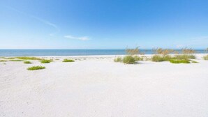 A sandy beach with sparse vegetation and a clear blue sky. - Seashells Unit 36 2 Bedroom Condo (Sanibel)