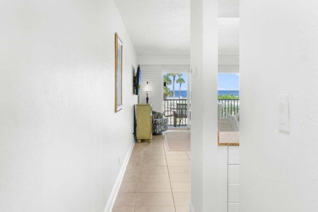 A corridor with a view to a balcony with a view of the ocean.