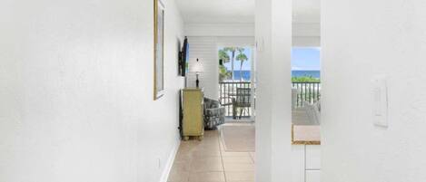 A corridor with a view to a balcony with a view of the ocean.