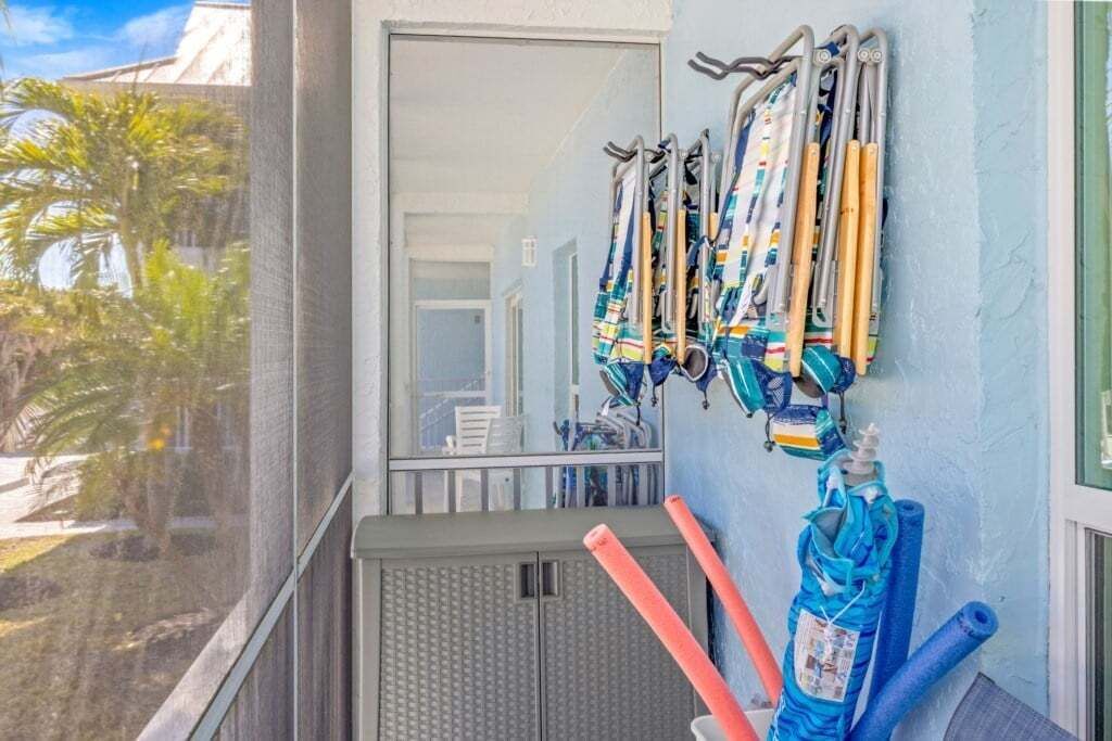 A balcony with a row of crutches and rolled-up mats against the wall.