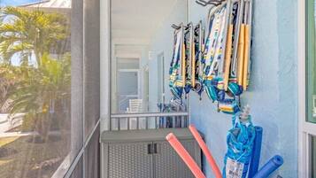 A balcony with a row of crutches and rolled-up mats against the wall.