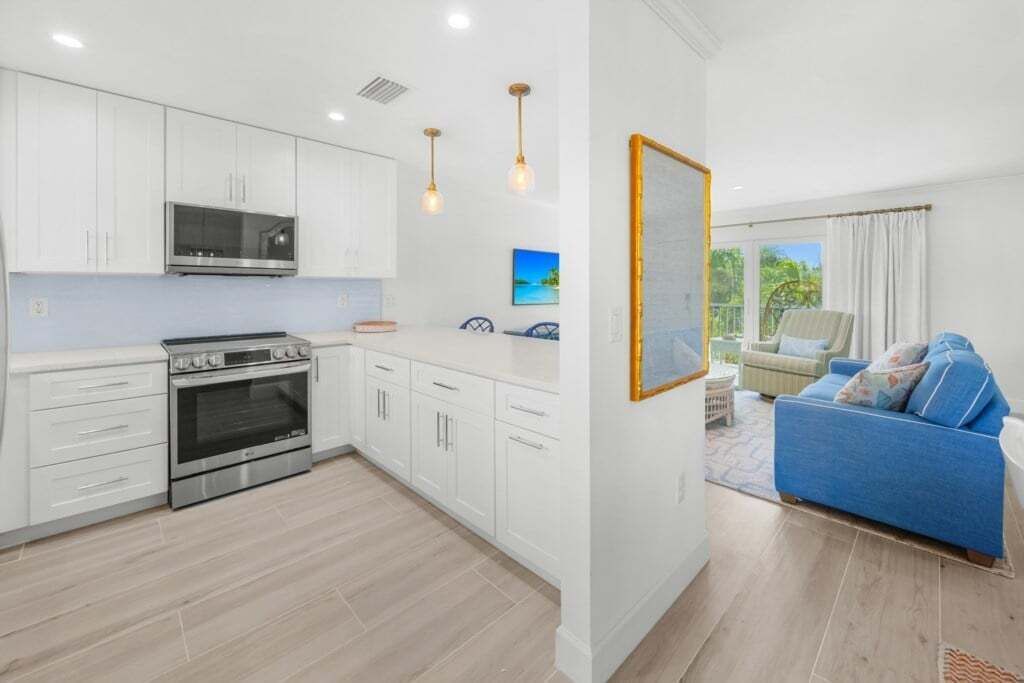 A modern kitchen with white cabinets, a built-in oven, and pendant lighting.