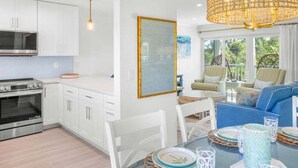 Ett modernt kök med vita skåp, en inbyggd ugn och en matplats med ett runt bord och stolar.
