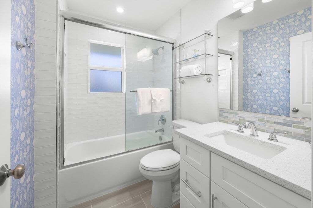 A modern bathroom with a glass-enclosed shower, a white toilet, and a vanity with a mirror.