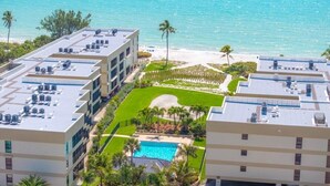 Un hôtel doté d’une piscine sur le toit, offrant une vue sur la plage et possédant une pelouse bien entretenue.