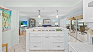 Une cuisine spacieuse dotée d’un grand îlot central, de luminaires suspendus et donnant sur un patio extérieur.