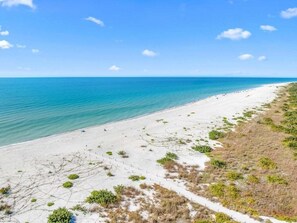 A beach with a clear view of the ocean and a sandy path leading to the water. - Blind Pass Unit E206 2 Bedroom Condo (Sanibel)