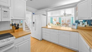 Una cocina moderna con armarios blancos, una encimera de madera y una estufa integrada.