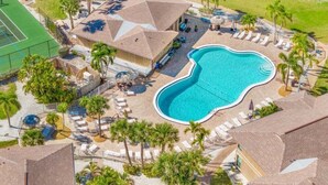 Un resort con piscina rodeada de tumbonas y palmeras.