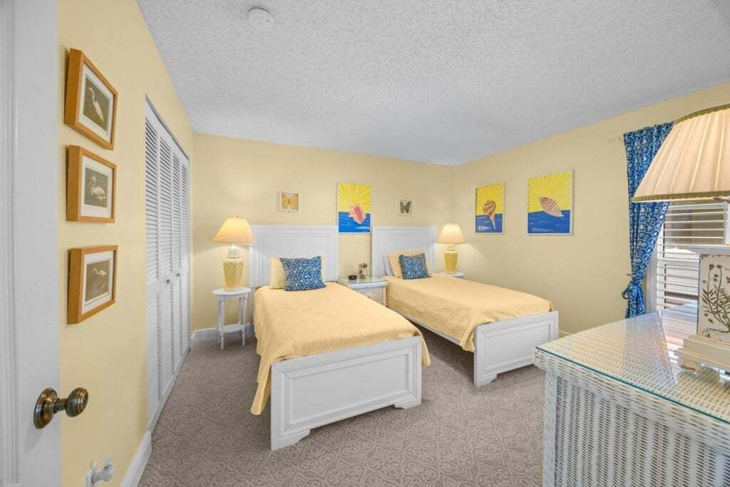 A room with two beds, a glass table, and wall art.