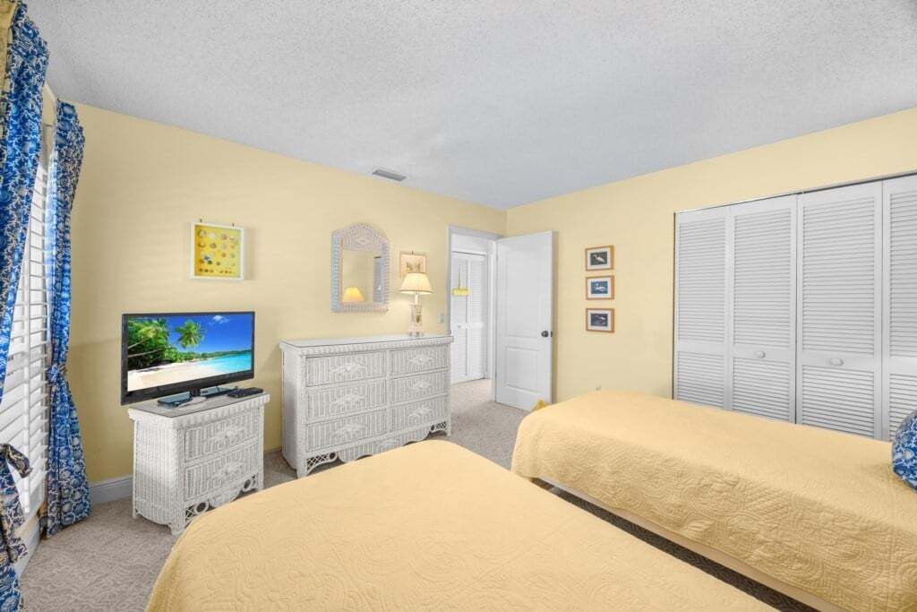 A bedroom with two beds, a TV, a dresser, and a wardrobe.
