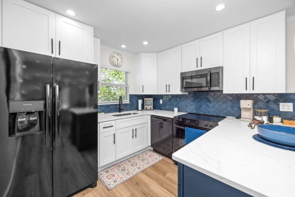 A modern kitchen with white cabinets, a black refrigerator, a microwave, and a blue countertop.