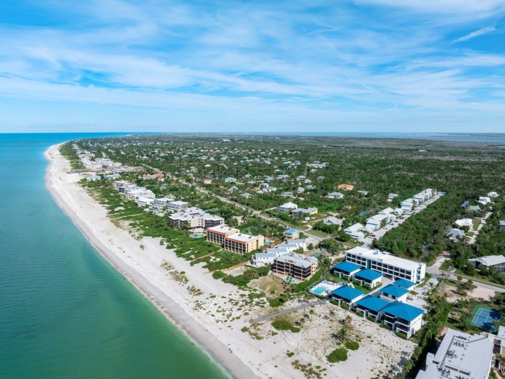 An aerial view of a coastal resort with beachfront properties, a beach, and a dense cluster of buildings.