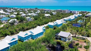 An aerial view of a resort with multiple buildings, a beach, and a clear blue sky. - Seashells Unit 12 2 Bedroom Condo (Sanibel)