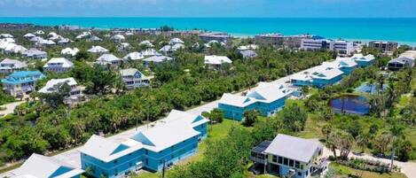 An aerial view of a resort with multiple buildings, a beach, and a clear blue sky.