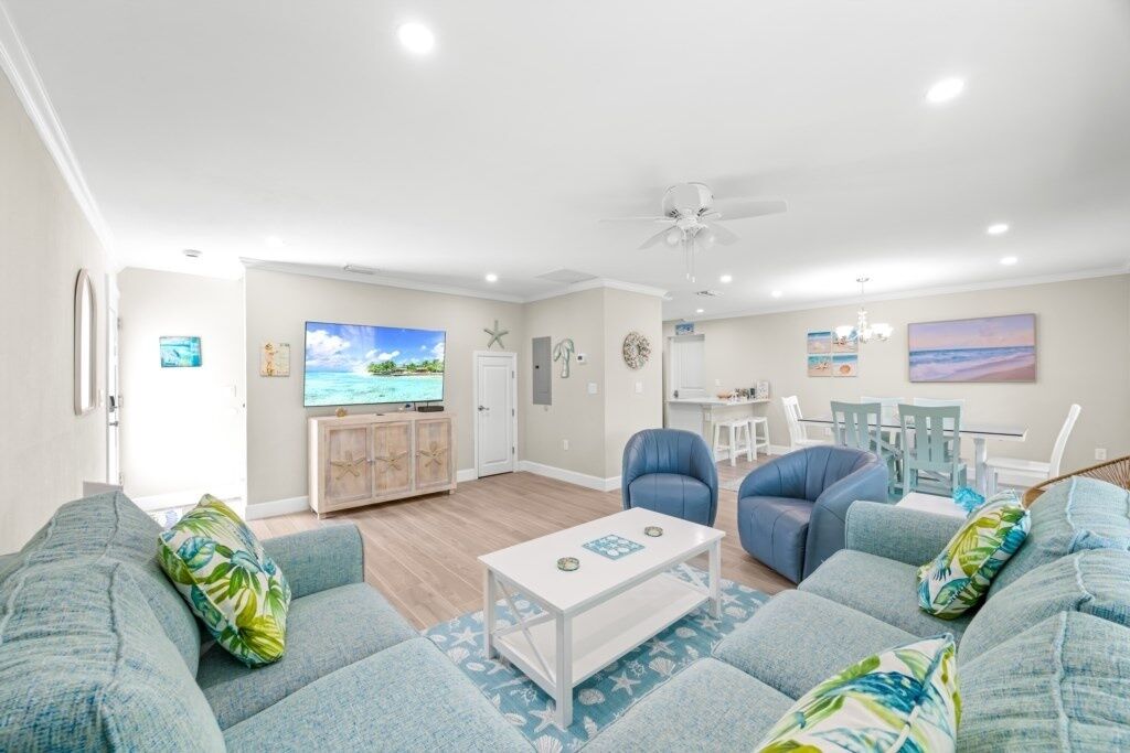 A living room with a TV, sofa, chairs, and a dining area with a table and chairs.