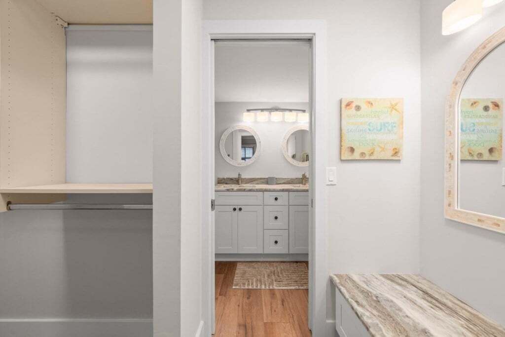 A bathroom with a vanity, two round mirrors, a sink, and a small rug on the floor.