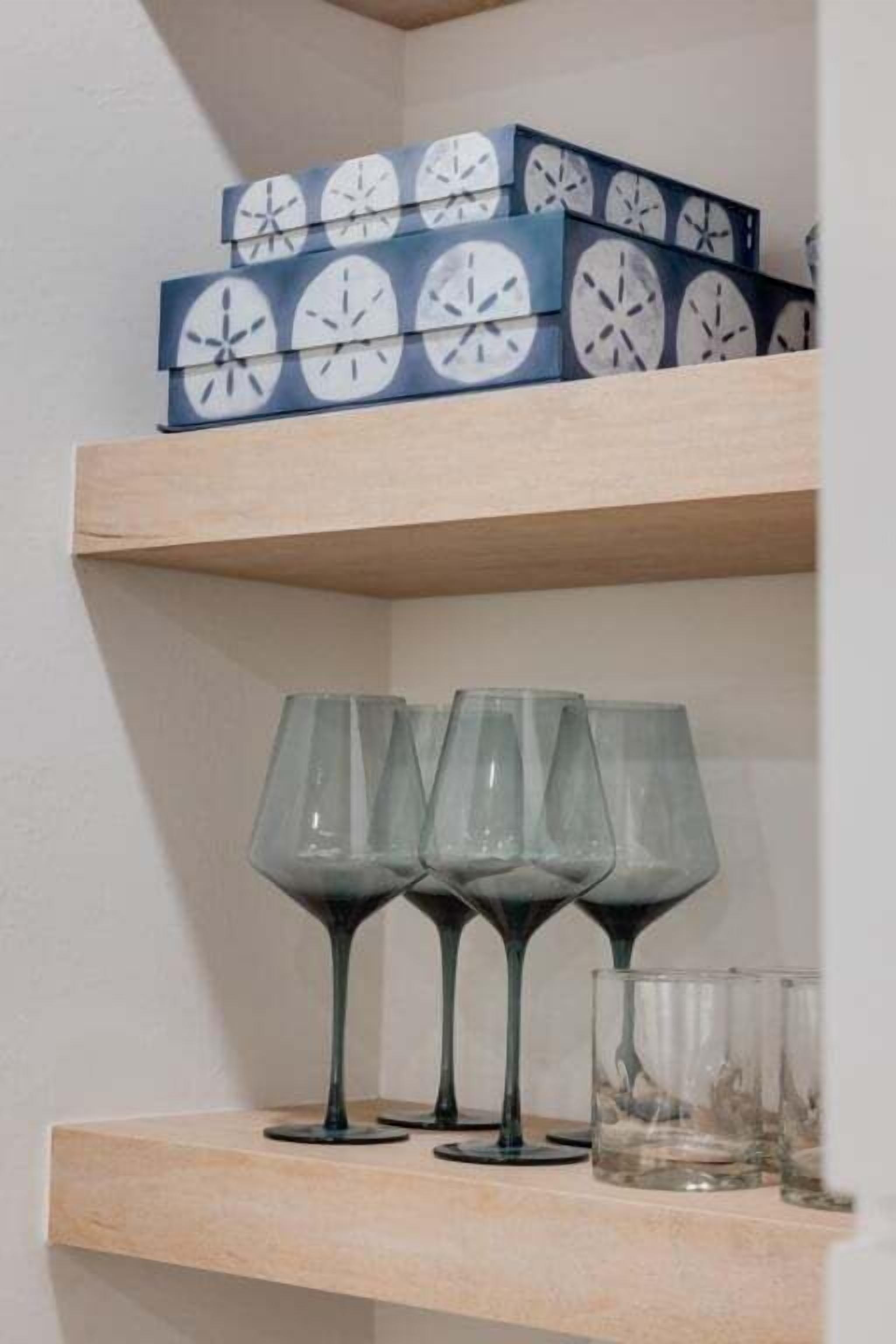 Une étagère avec des boîtes décoratives et des verres à vin.