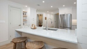 A modern kitchen with white cabinetry, a stainless steel refrigerator, and a marble countertop. - Sanddollar A302 3 Bedroom Condo (Sanibel)