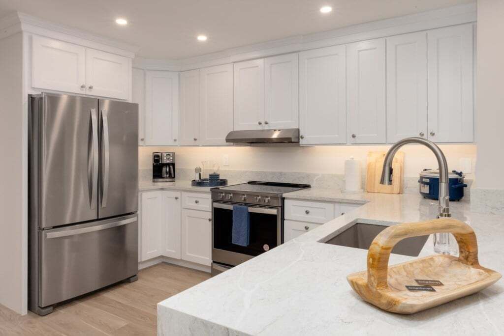Una cocina moderna con armarios blancos, electrodomésticos de acero inoxidable y encimera de mármol.