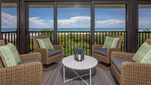 A balcony with wicker furniture and a view of the ocean. - Sanddollar A302 3 Bedroom Condo (Sanibel)